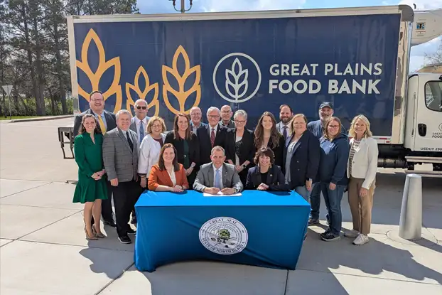 ND Governor Armstrong signs House Bill 1143 surrounded by supporters, marking a $5 million state investment in a new statewide food distribution center through a public-private partnership.